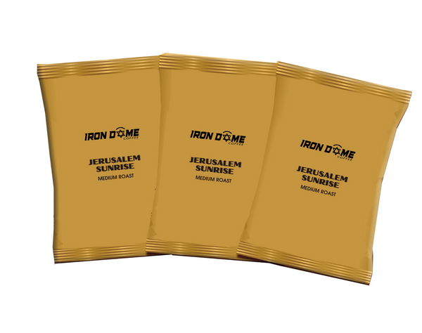 Three gold coffee packages labeled 'Iron Dome Coffee Jerusalem Sunrise Medium Roast' on a white background.