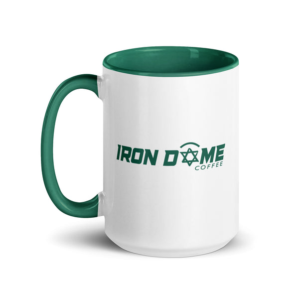 A ceramic coffee mug with a green rim, handle, and interior, featuring white body with 'IRON DOME COFFEE' text and design.